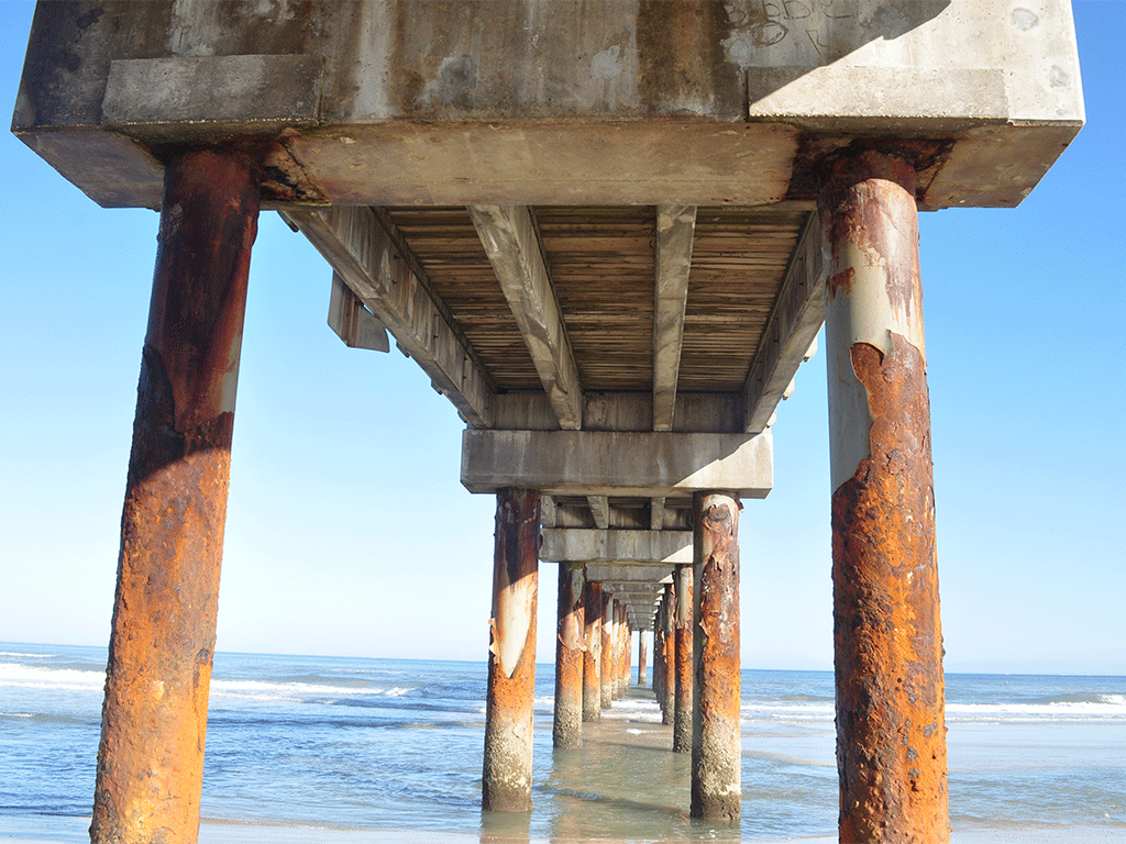 St. Johns County Ocean and Fishing Pier in St. Augustine Beach with visible pier pilings over the sand and ocean.