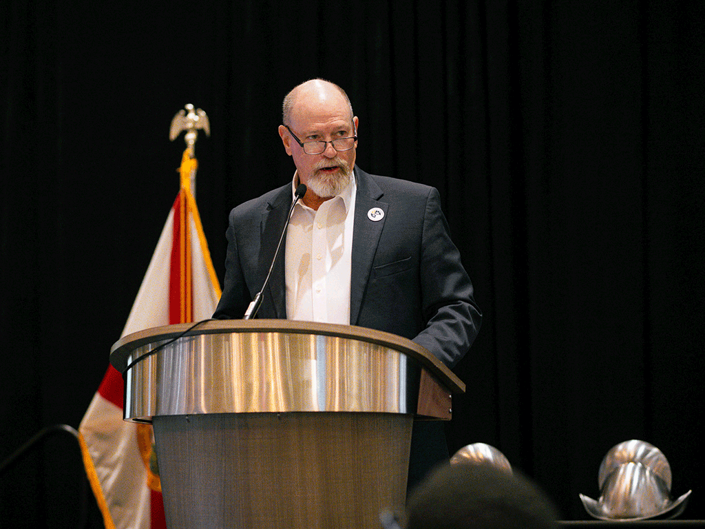 Commissioner/Chair Murphy speaks into a microphone at a podium