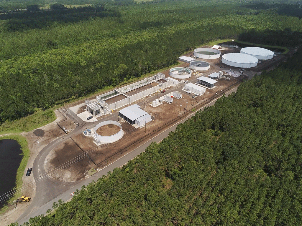 Aerial view of reclaimed water facility with storage tanks, surrounded by wooded greenspace