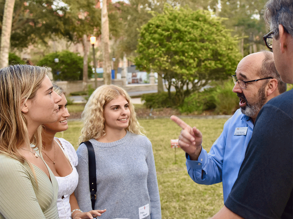 Man lecturing three students in an outdoor setting