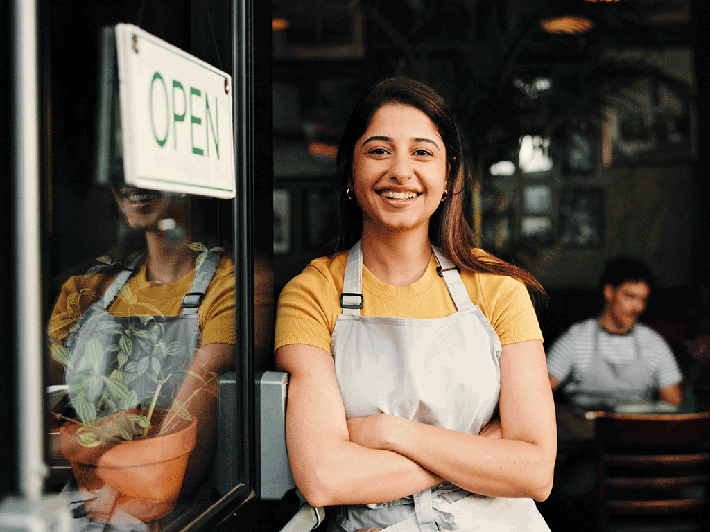 Business owner smiling in front of an Open sign