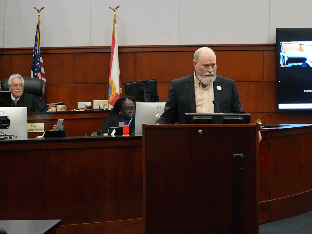 Commissioner speaking from podium in a court room setting.