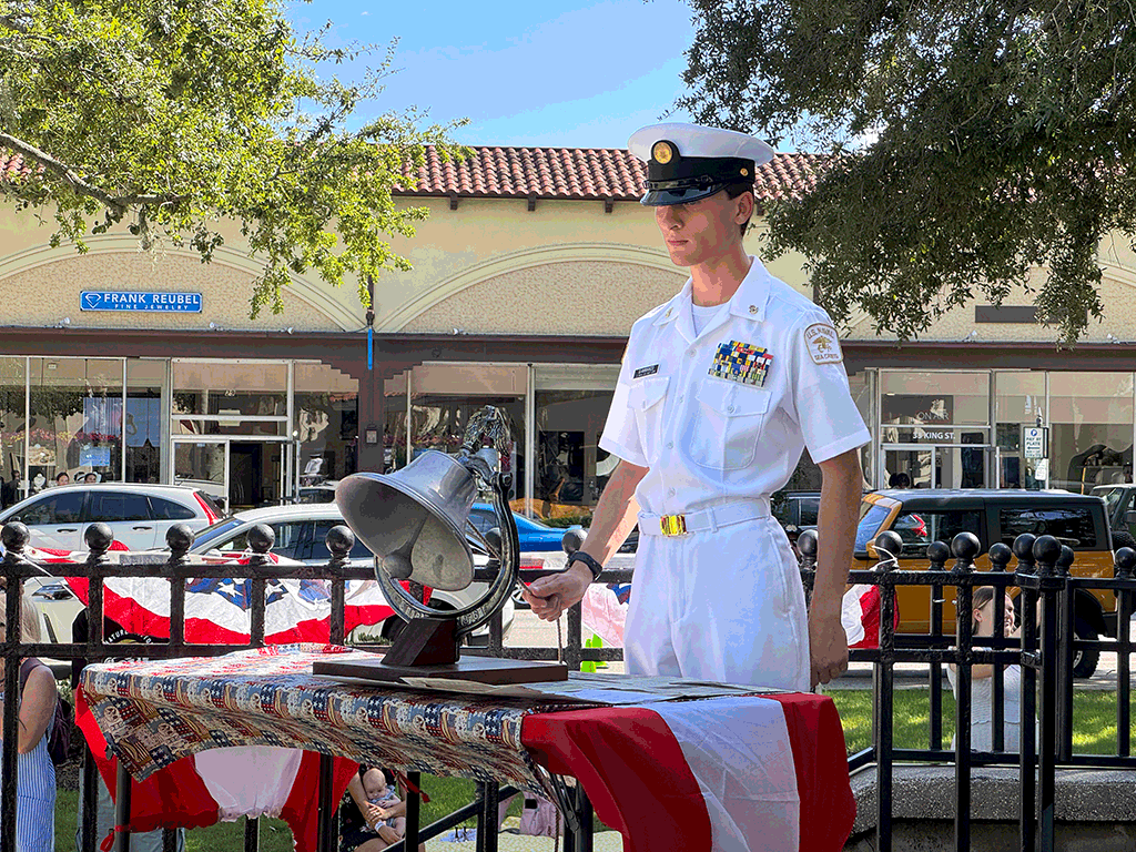 Young man in decorated military uniform standing outside ringing bell.